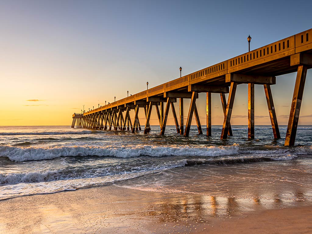 A view from the beach in Wrightsville Beach, NC, towards the Atlantic Ocean with the town fishing pier on the right of the image extending into the ocean