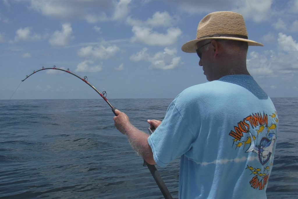 An angler attempts to reel in something on the end of his line while deep sea fishing in Galveston