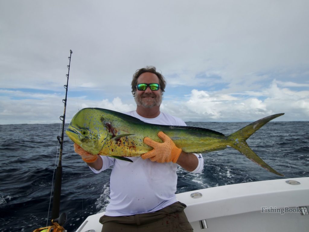 a smiling angler holding a large Mahi Mahi on a fishing boat near Quepos, Costa Rica