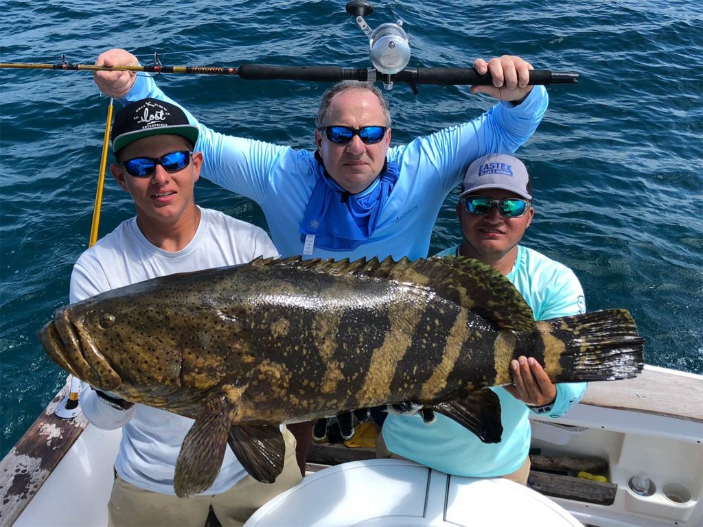 Three anglers hold a Grouper caught in Los Sueños