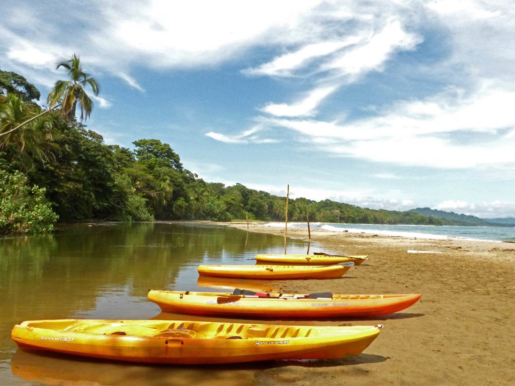 Three kayaks lie on the sand next to the inshore waters on Costa Rica's Pacific coast