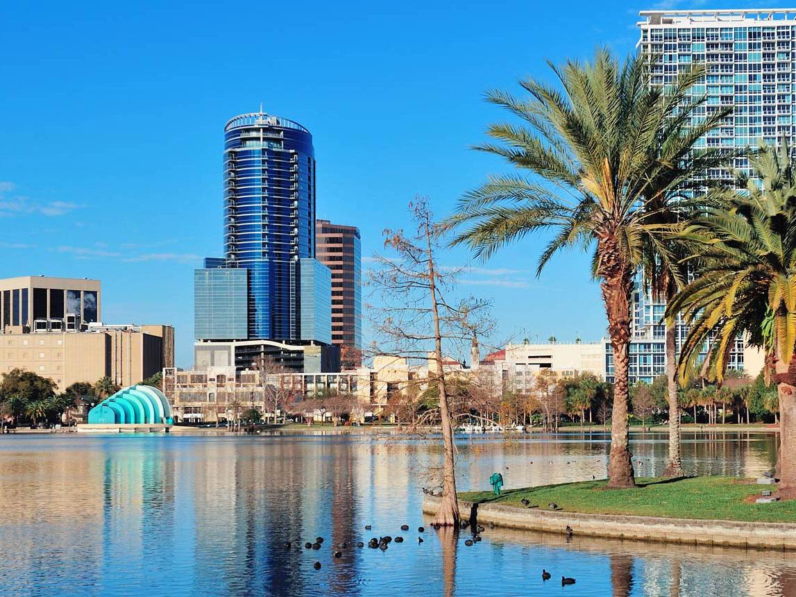 Downtown Orlando viewed from a lake with palm trees in front of the buildings