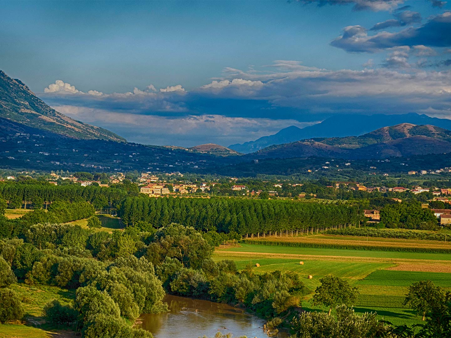 A view of the Volturno River flowing through a valley in Italy on a sunny day