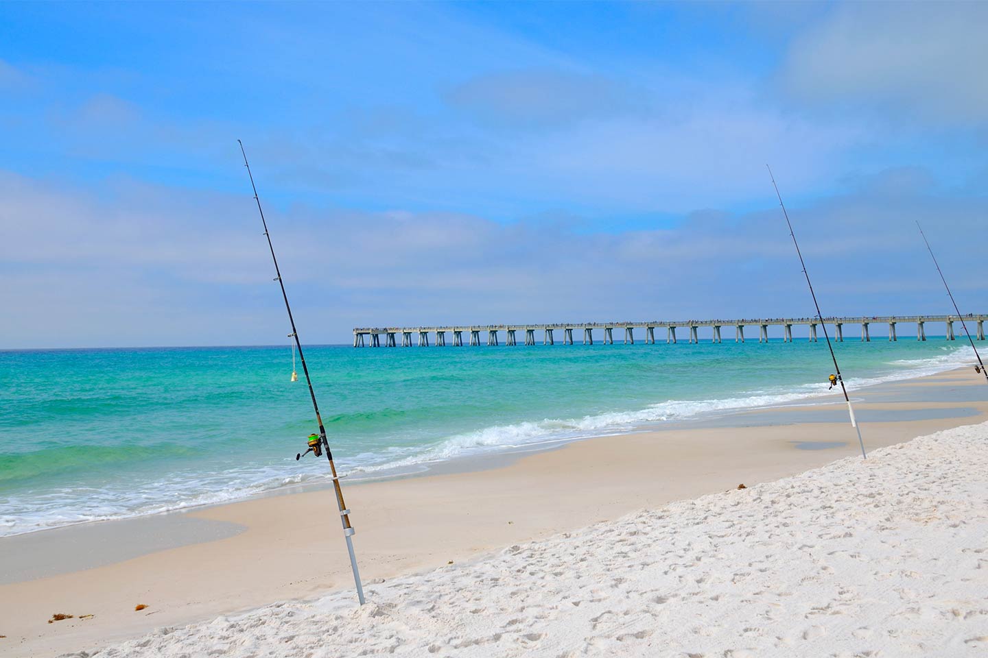 Three fishing rods perched on Panama City Beach, Florida.