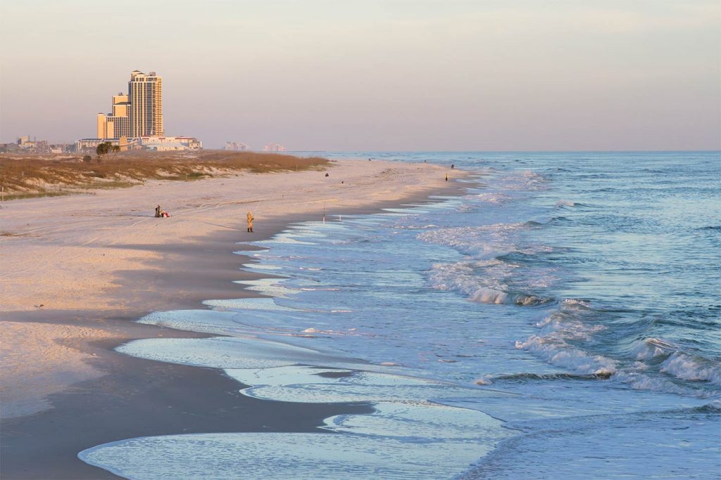 A view of Gulf Shores beach towards the town with anglers lined along the sand casting into the Gulf of Mexico