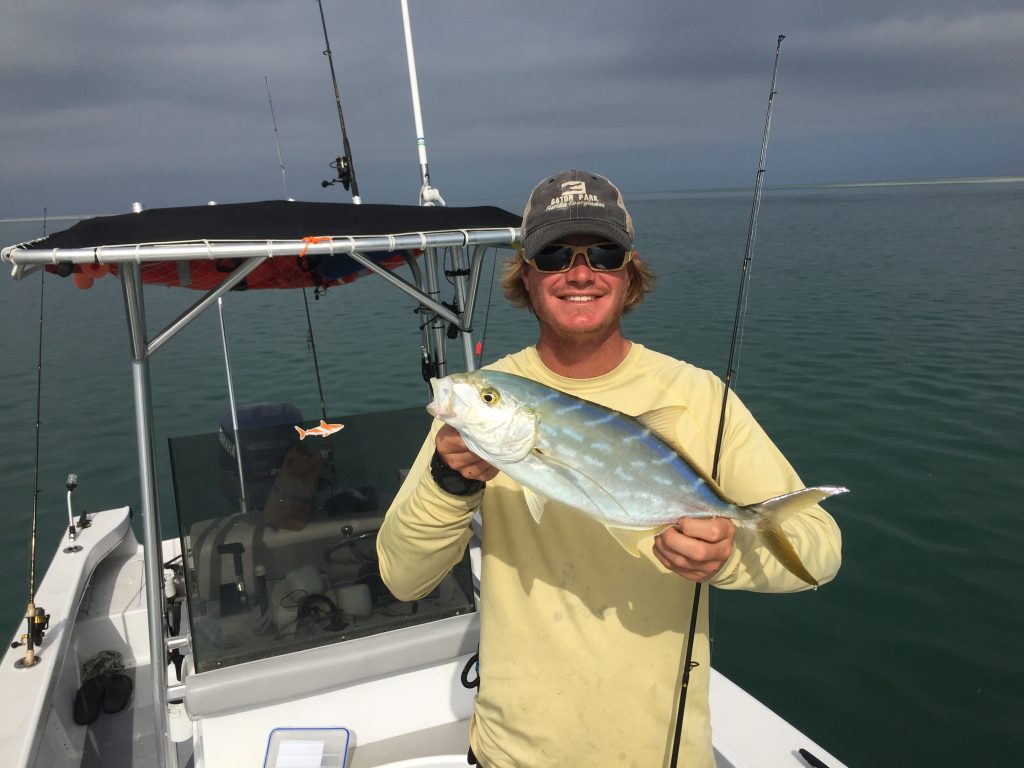 a smiling angler holding a fish on a fishing boat near Key West