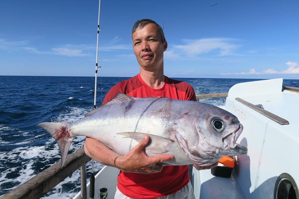 an angler holding a fish on a fishing boat near Tauranga