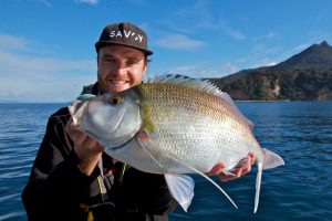 an angler holding a Kingfish (Yellowtail Amberjack) on a fishing boat near Auckland