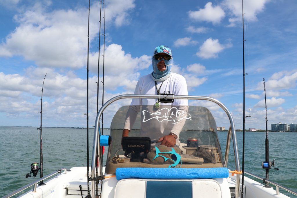 A Captain driving a boat with blue skies and water as background