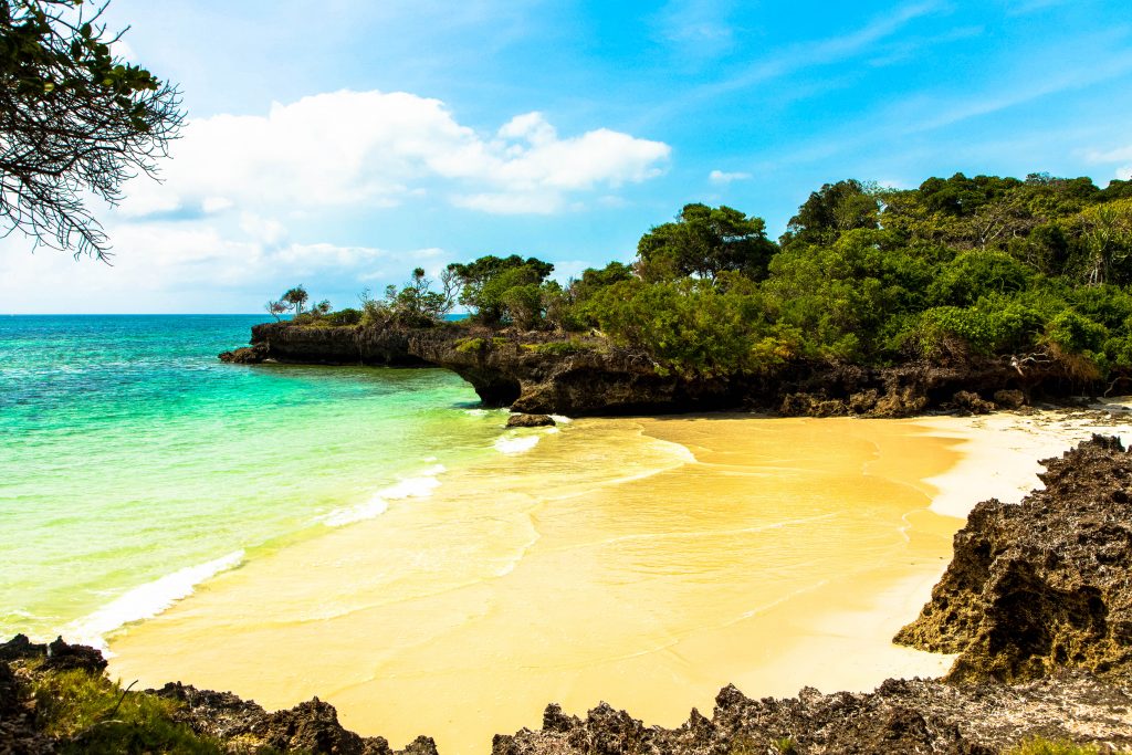 Chale island, Kenya, showing a small beach and the water with some small cliffs on a sunny day