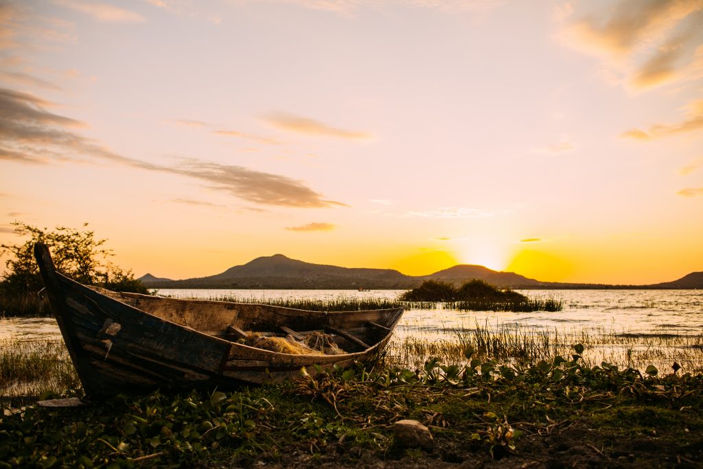 a boat on a beach on Lake Victoria, Kenya, with the sun setting in the background