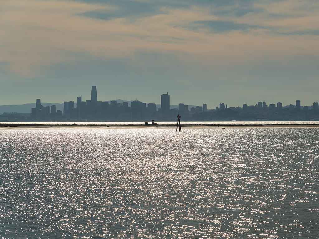 A view across the waters of the San Francisco Bay towards San Francisco from Richmond on a bright day, with the waters glistening in the image