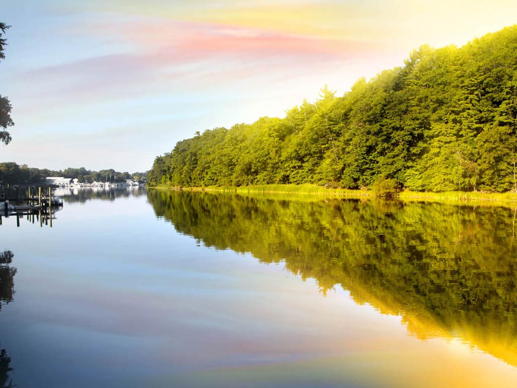 A view of Lake Michigan surrounded by lush forests during the sunset