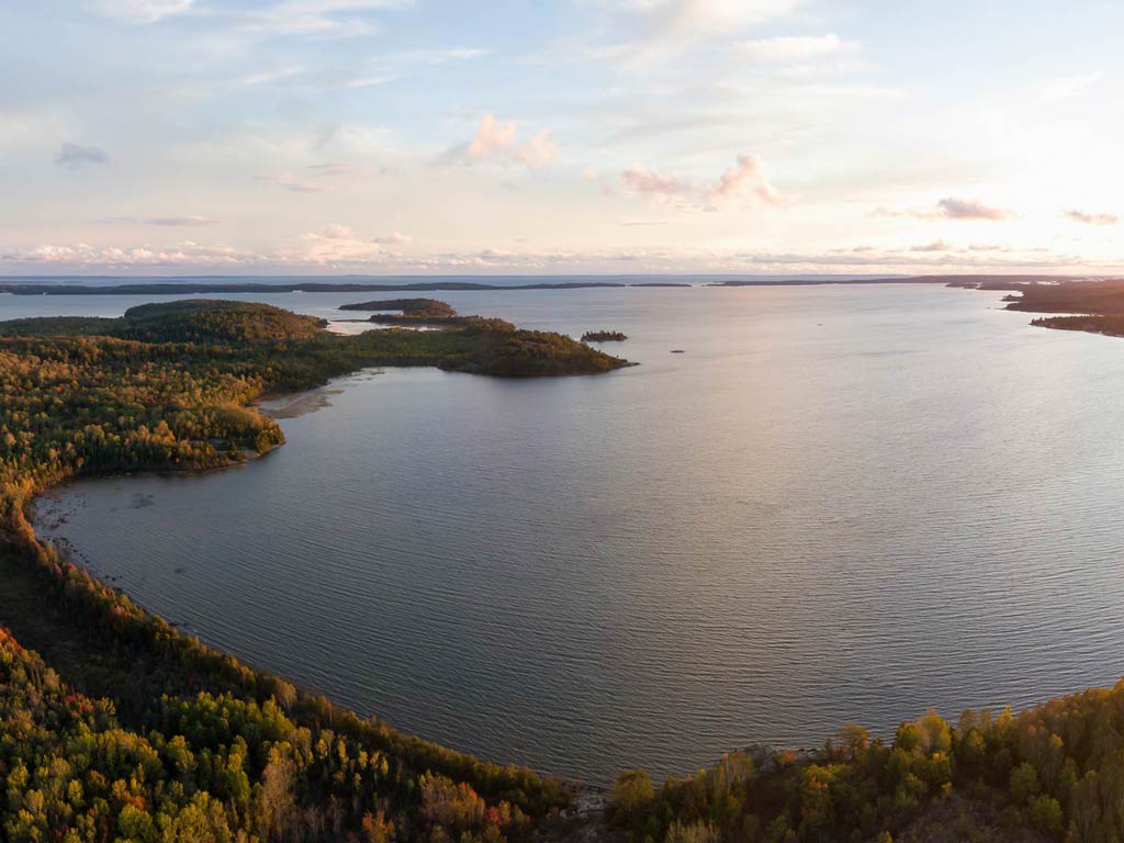 An aerial view of Lake Huron and surrounding forests as seen during the fall season