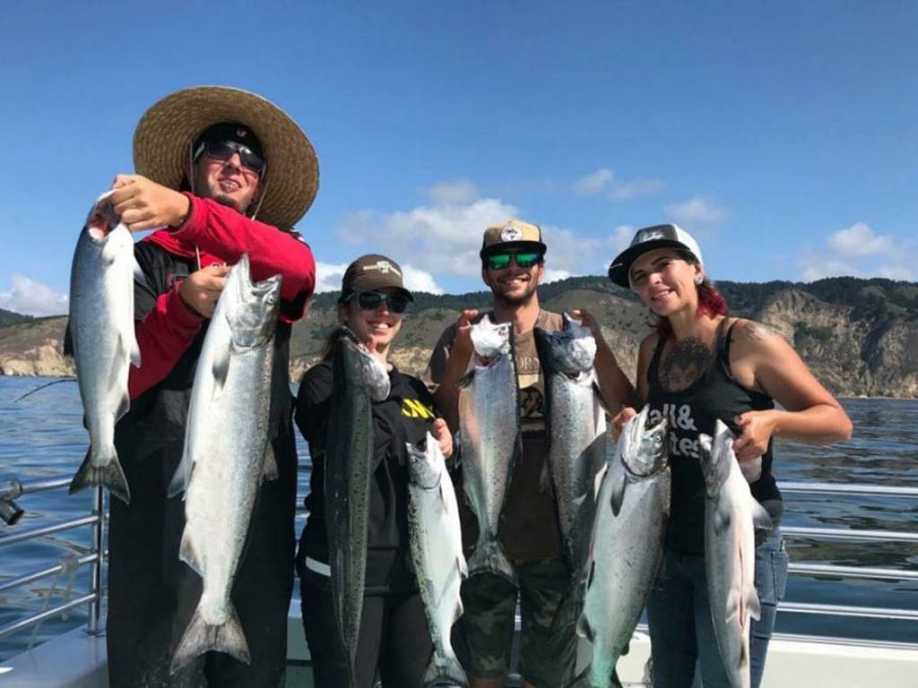 A photo featuring four anglers posing with Salmon each.