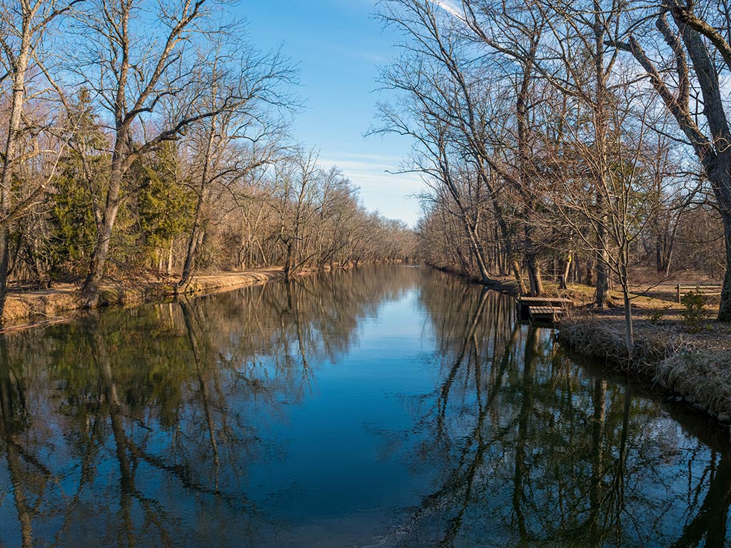 A view down the Delaware and Raritan Canal on a fall day, with barren trees visible on either side of the water