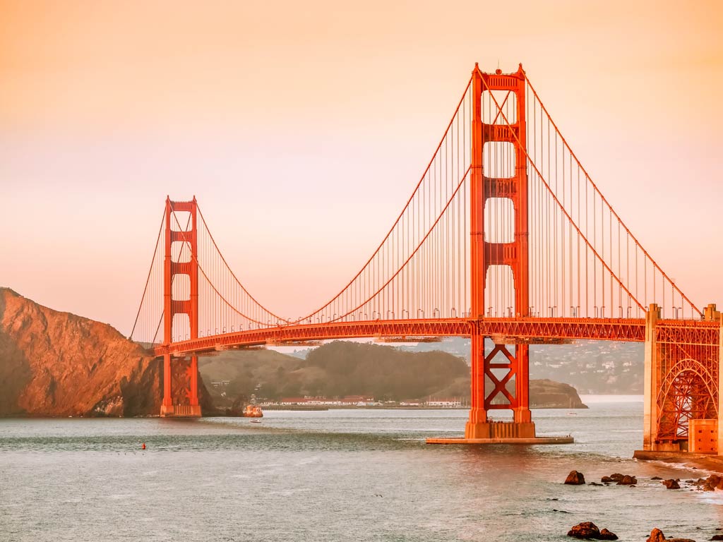 A magnificent view of the vibrant Golden Gate Bridge seen from the side during the early morning and foggy season in San Francisco
