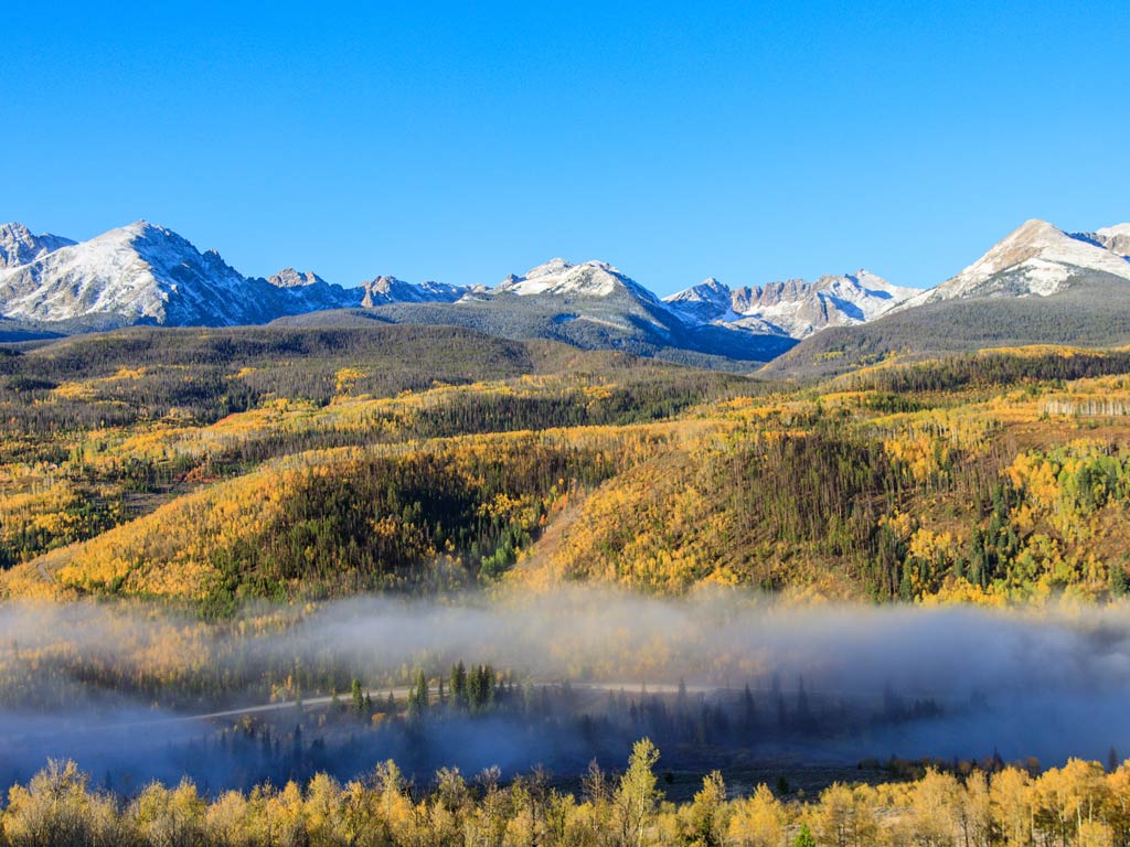 A magnificent aerial view of the Blue River location engulfed in Silverthorne’s evergreen forests and snow-capped mountains during the Thanksgiving fishing season