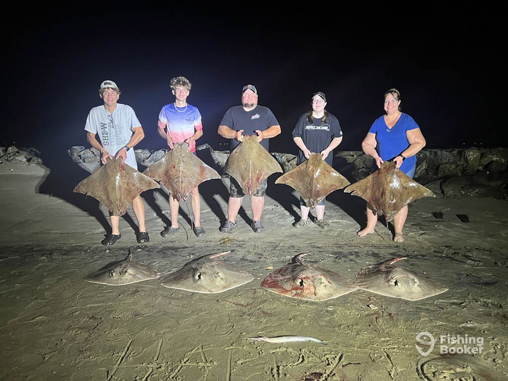 A group of 5 people standing and holding a Ray each with another Ray lined up in front of every one of them at night