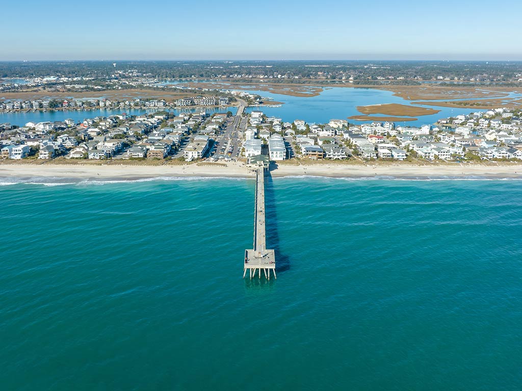 An aerial view looking towards the Johnnie Mercers Fishing Pier in Wrightsville Beach, near Carolina Beach on a clear day, with clear waters in the foreground