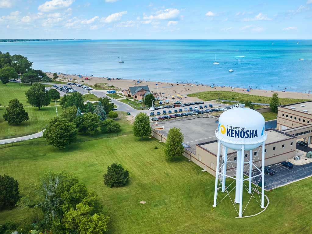A view of Kenosha waterfront with a water tower in the foreground and Lake Michigan stretching in the distance on a day with sunny intervals.
