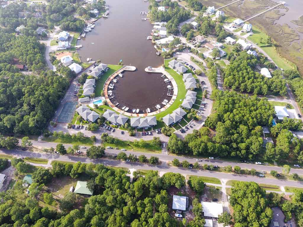 An aerial view of Dauphin Island, one of the best Red Snapper fishing destinations in the Gulf, showing the town's marina and boats docked in a circle behind the main highway.