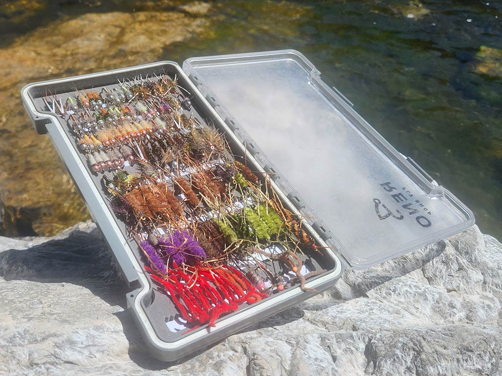 A plastic fly box filled with colorful artificial fishing nymph fly fishing flies.