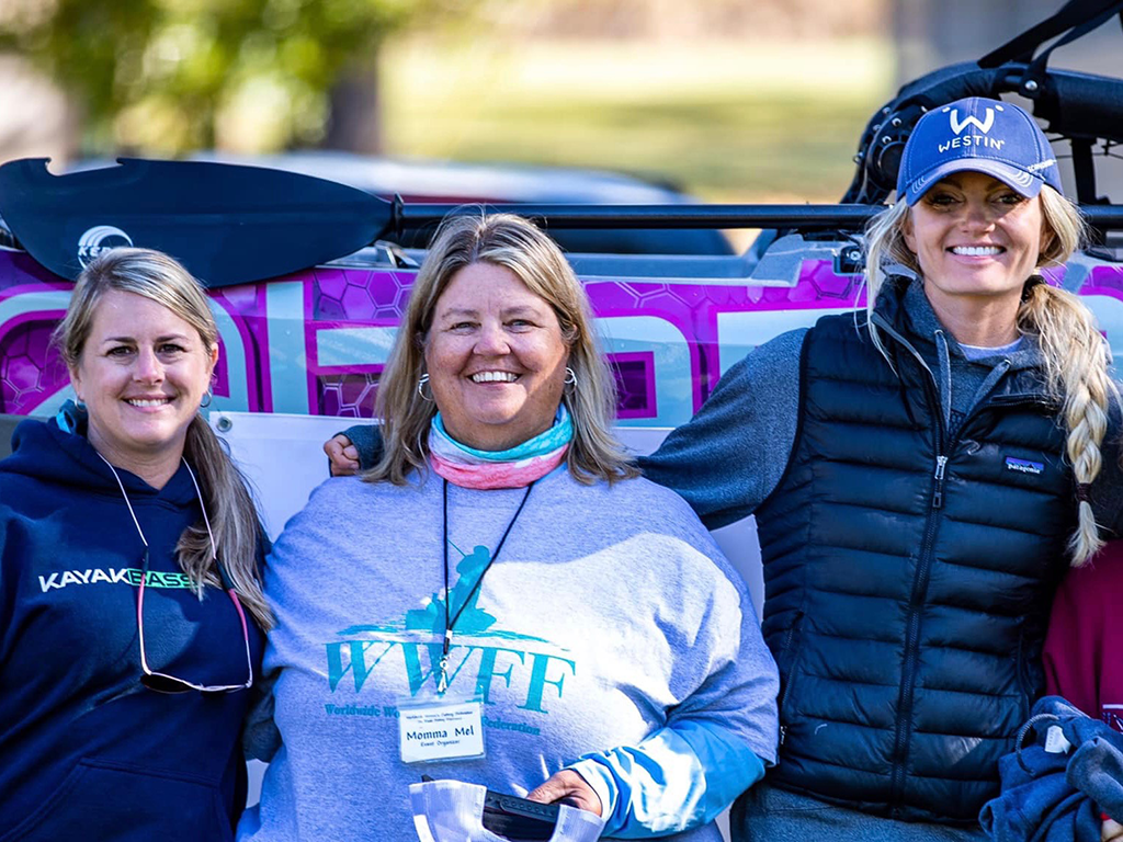A photo of three women, proudly standing at a fishing event they organised for the Women's Fishing Federation.