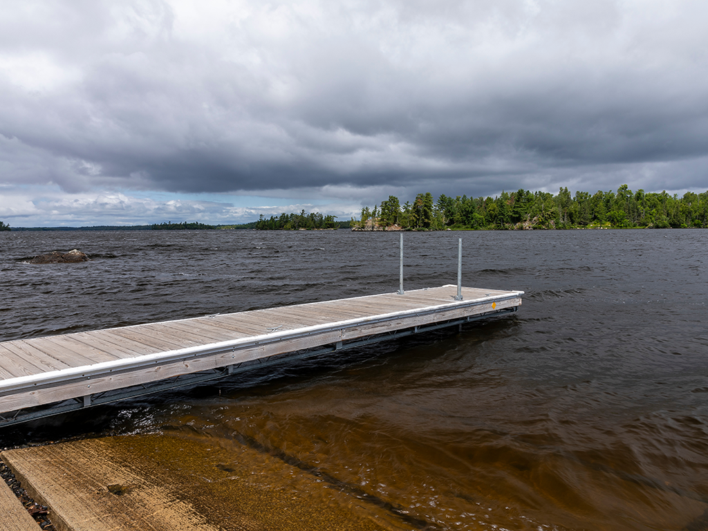 A view of a dock sticking out into the murky waters of Lake Vermilion on a cloudy day.