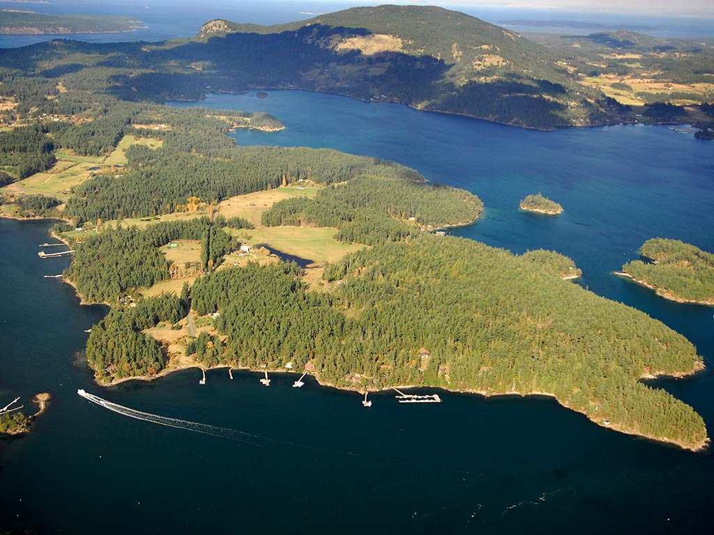 An aerial view of the San Juan Islands, showing the sparse, green islands in dark blue water.