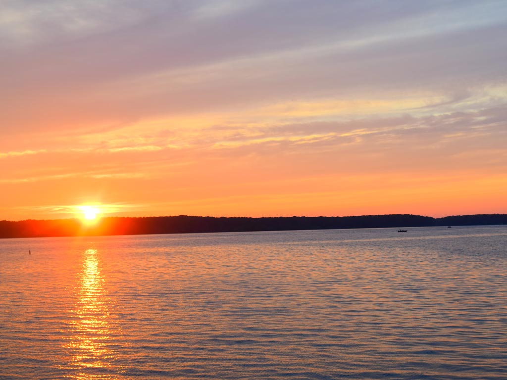 A sunset over Mosquito Lake in Ohio, with the sun painting both the lake and the sky in an orange hue.