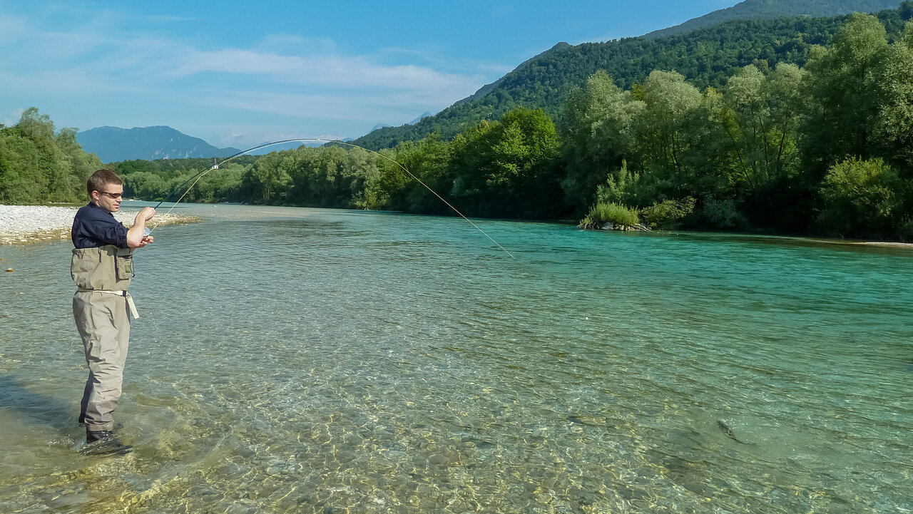 Ein Angler f&auml;ngt einen Fisch am Zusammenfluss der Soča und dem Tolminka.