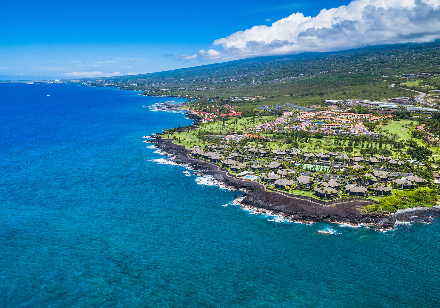 Eine Luftaufnahme von Kailua-Kona, Hawaii, mit blauem Meer links und der Insel rechts.
