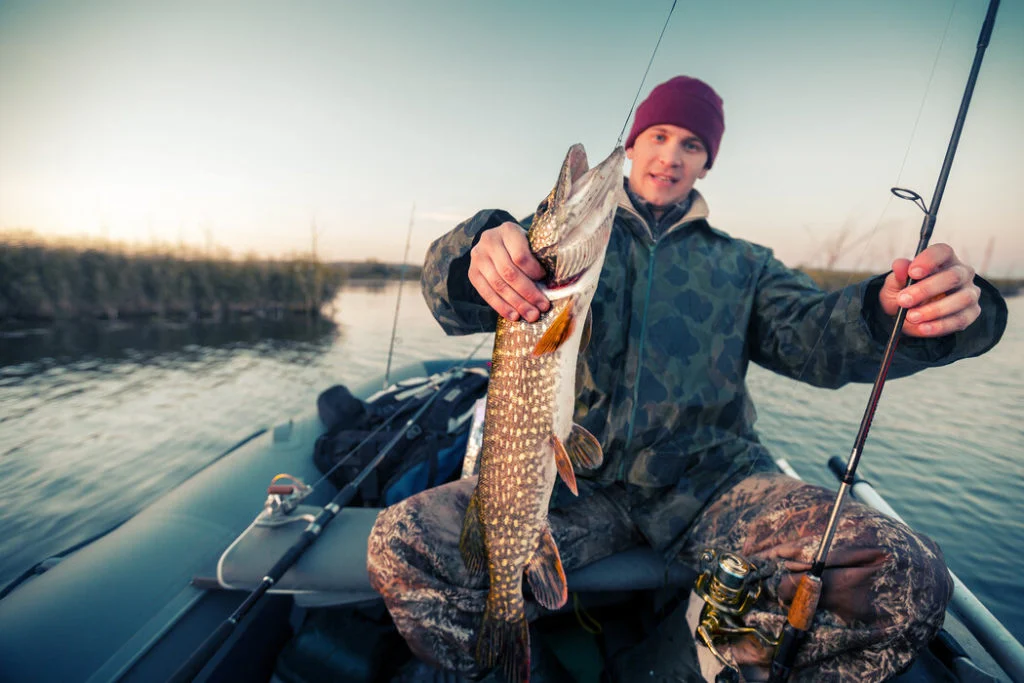 Angler in einem Boot mit Hecht.