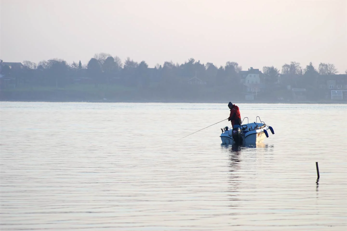 Ein Angler, der in der Provinz Seeland in D&auml;nemark auf seinem Boot angelt.