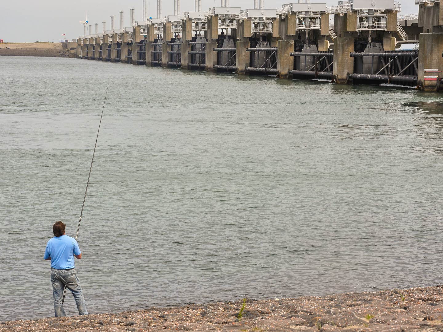 Mann, der neben dem Gro&szlig;en Deich von Oosterschelde angelt.