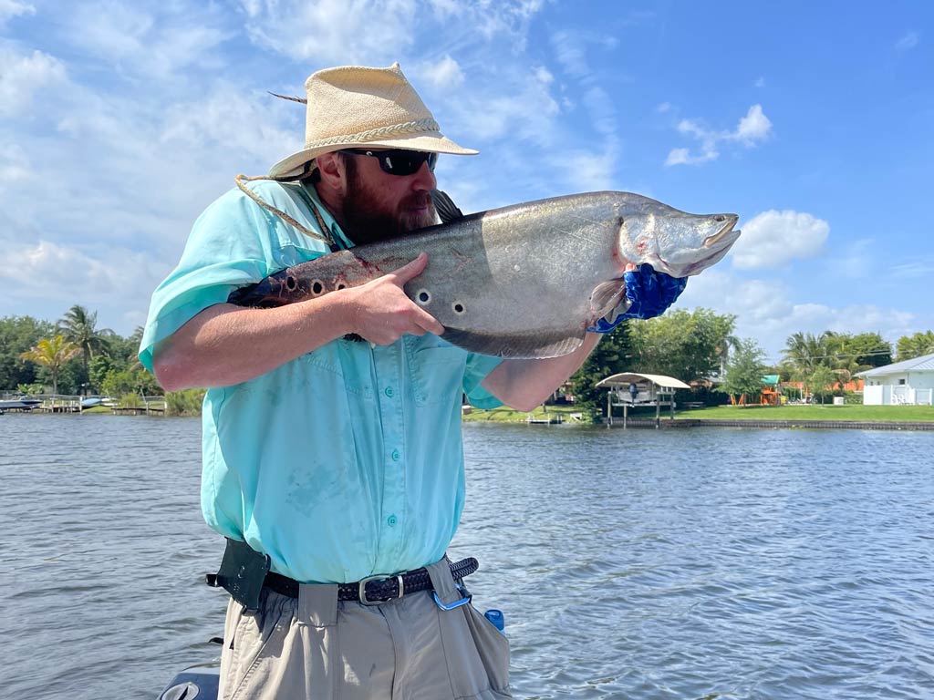 Drew Pawley, FishingBooker’s most passionate angler, clowning around while posing with a Clown Knifefish he caught.