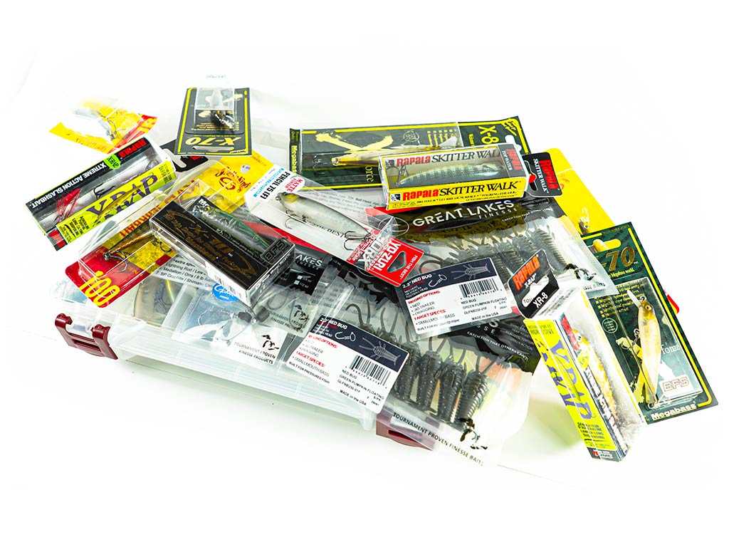 A mix of packaged fishing lures and tackle supplies, just right for Wisconsin Bass fishing, spread out on a clear plastic tackle box.