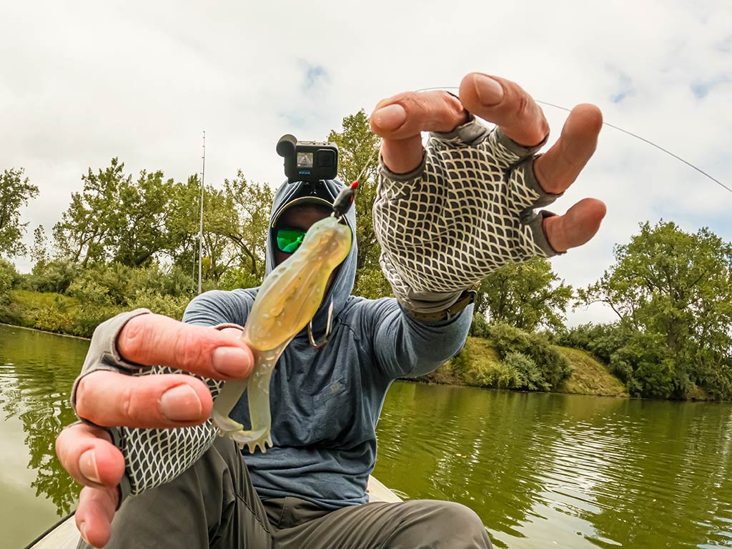 A man showing a lure to the camera, ready for pond fishing on a cloudy day.