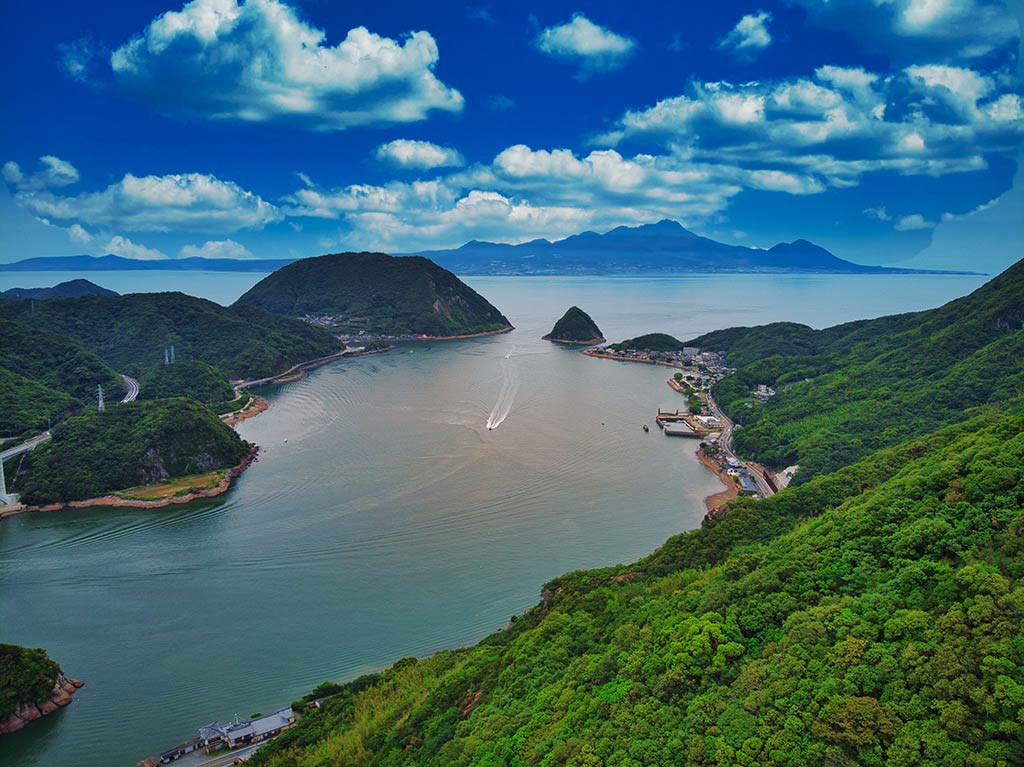 An aerial view of a remote river leading into the ocean in Japan, with visible hills making it a scenic picture.