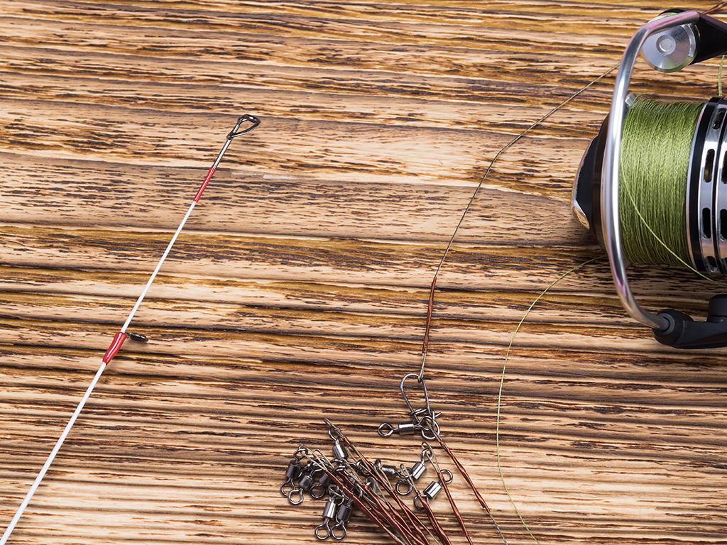 A fishing reel, line, and other equipment laid out on a wooden table.