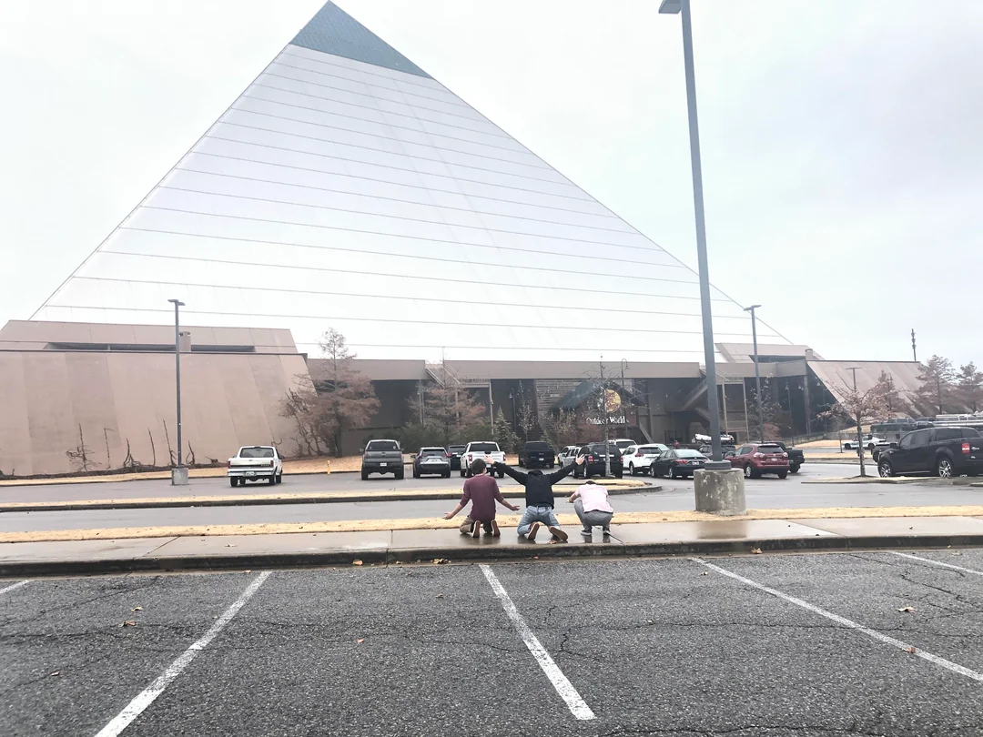A photo of the Bass Pro Pyramid in Memphis, Tennessee and three men kneeling in front of it.
