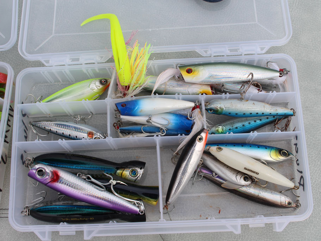 Пластиковый ящик для рыболовных снастей с разнообразными яркими приманками, аккуратно разложенными по отсекам