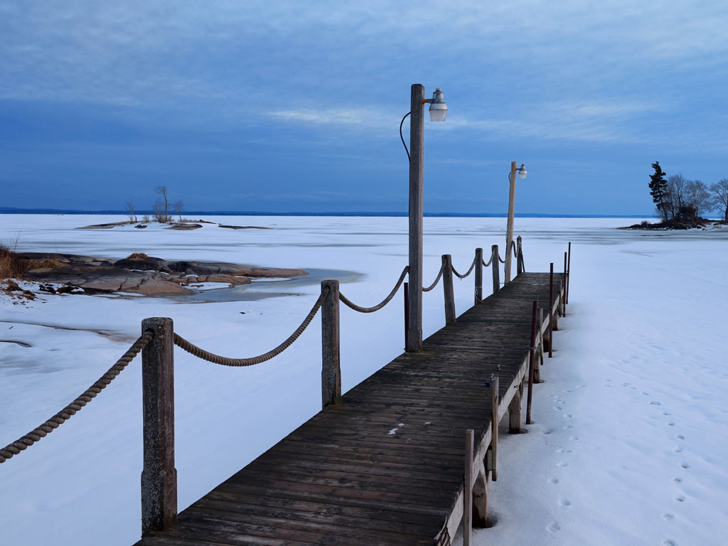 A wooden dock with rope railings stretches over a frozen Lake Nipissing, one of the best ice fishing destinations in Canada.