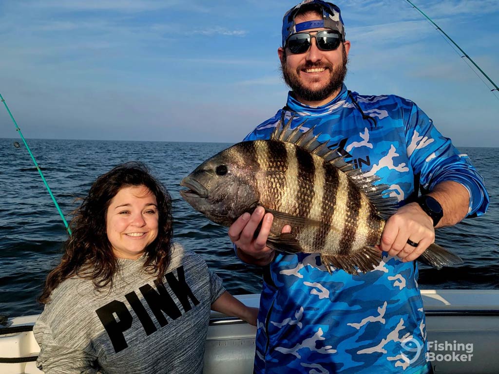 Two anglers on a boat pose with a large Sheepshead in Tybee Island – a premier winter fishing destination. A male angler is holding the fish while a female angler stands beside him, smiling.
