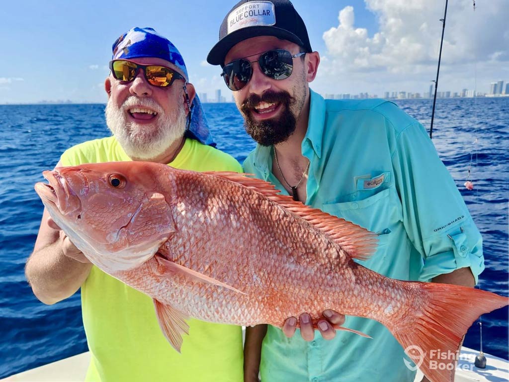 A photo featuring two proud and smiling anglers posing with a big Red Snapper after bottom fishing off the Atlantic Coast in Florida