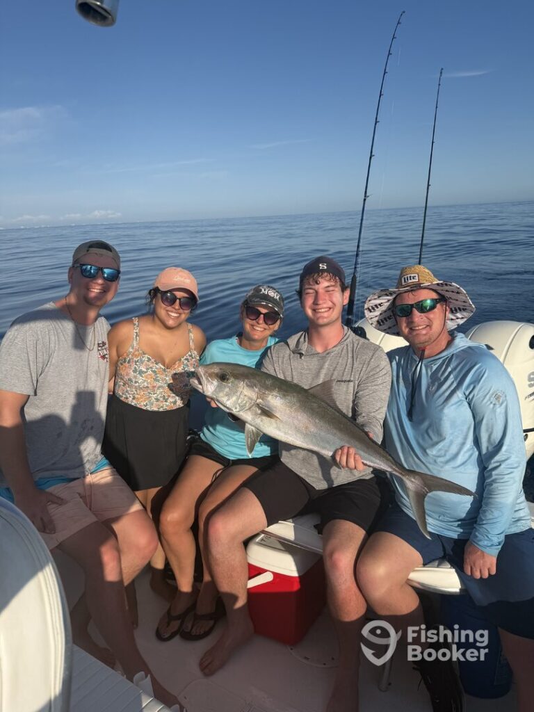 Five people on a boat are posing with a large Amberjack, enjoying the season. Two fishing rods and a calm sea set the perfect background, and everyone's clearly having a great time.