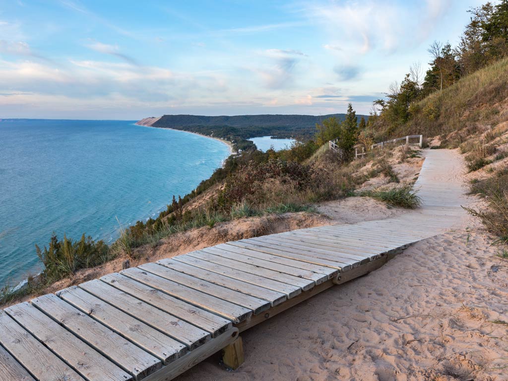 A wooden boardwalk curves along sandy Sleeping Bear Dunes overlooking Grand Traverse Bay