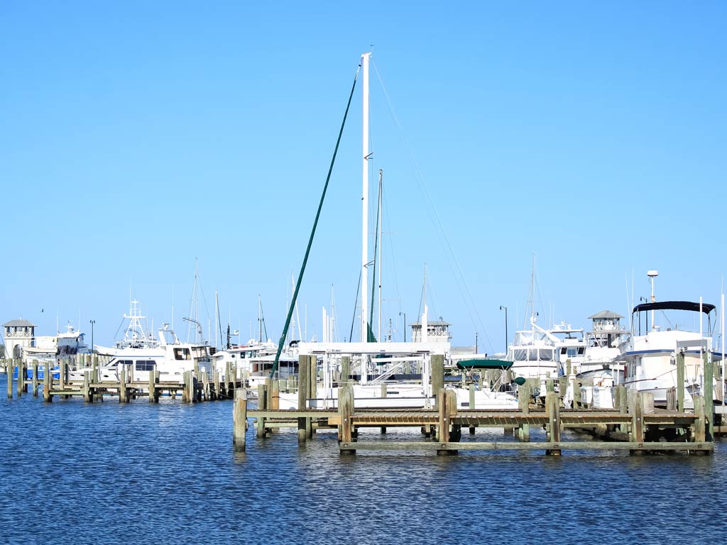 A view of Gulfport Marina with several docked boats and yachts sitting under a clear blue sky.