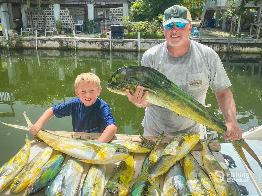 A man and a boy show off several large fish, including a Mahi-Mahi, on a dockside table in the Florida Keys.